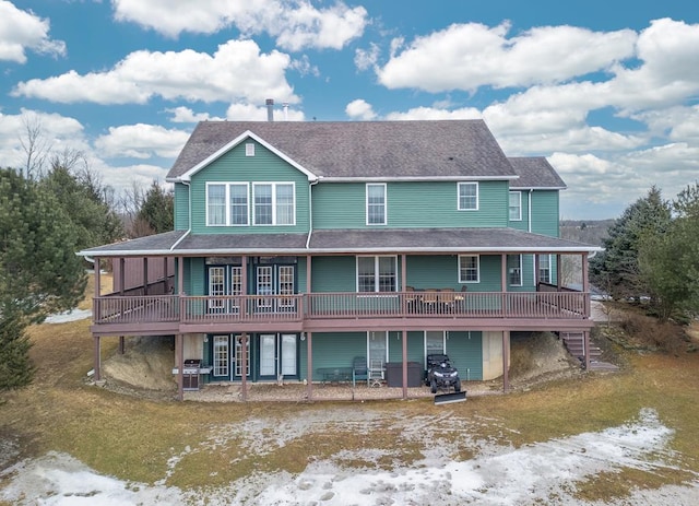 back of property featuring a deck, a patio area, a lawn, and roof with shingles