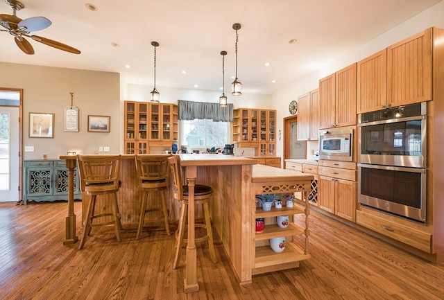 kitchen featuring open shelves, wood finished floors, light countertops, and stainless steel appliances