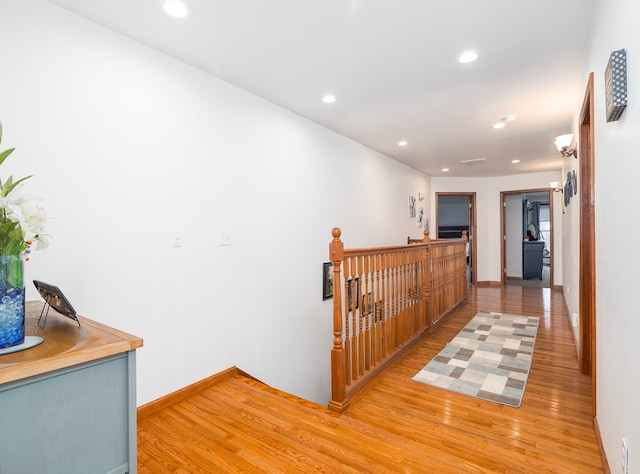 corridor featuring an upstairs landing, recessed lighting, light wood-type flooring, and baseboards