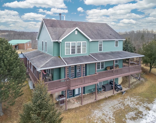 rear view of house featuring a wooden deck, driveway, and a shingled roof