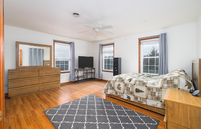 bedroom with light wood-style flooring, a ceiling fan, and visible vents