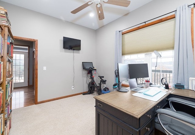 office space with baseboards, light colored carpet, and a ceiling fan