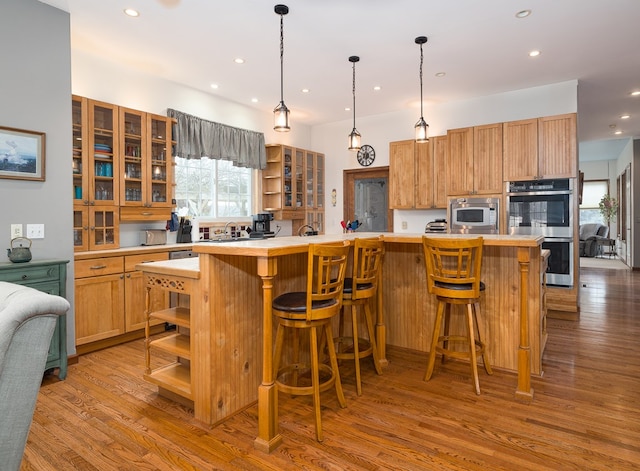 kitchen with open shelves, stainless steel appliances, wood finished floors, and light countertops