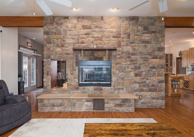 living room featuring beamed ceiling, wood finished floors, and a ceiling fan