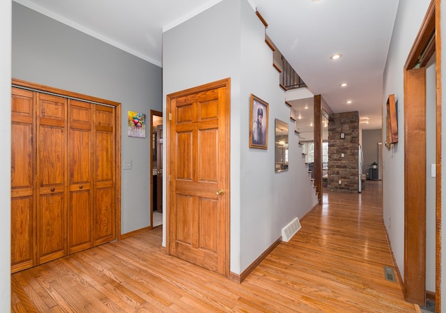 hallway featuring visible vents, light wood-type flooring, and baseboards