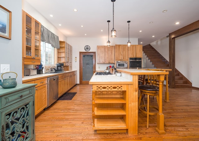 kitchen with light wood finished floors, open shelves, a center island, appliances with stainless steel finishes, and a sink