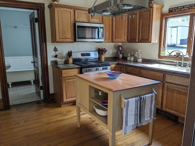 kitchen with sink, stainless steel appliances, wood counters, extractor fan, and hardwood / wood-style flooring