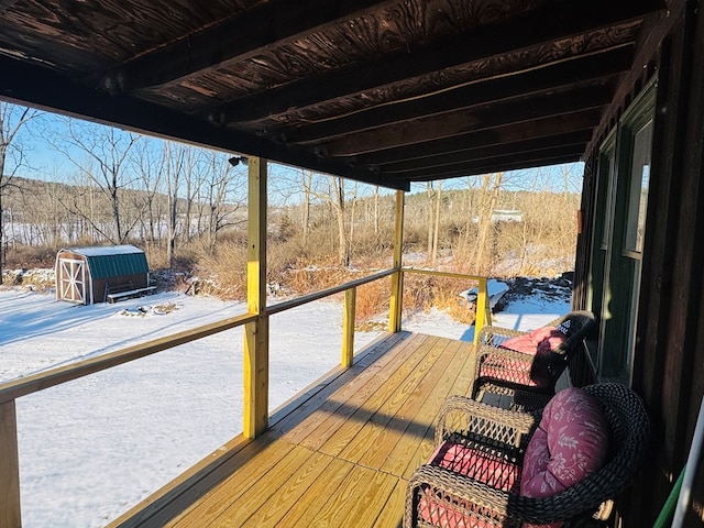 snow covered deck featuring a storage shed