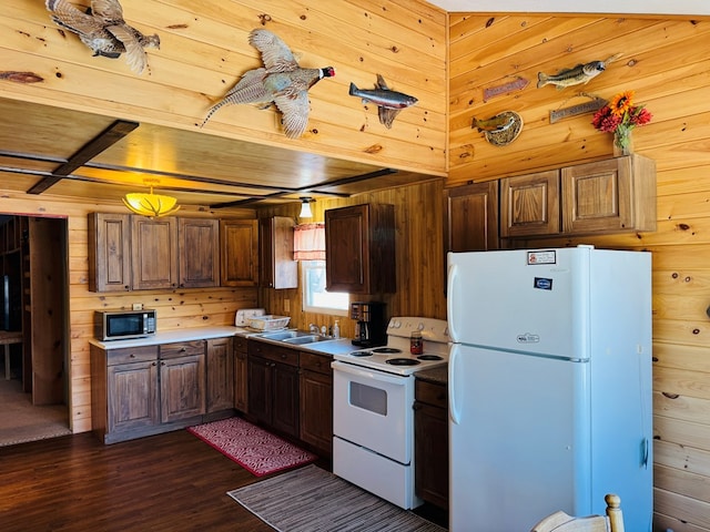 kitchen with wood walls, sink, white appliances, dark wood-type flooring, and beam ceiling