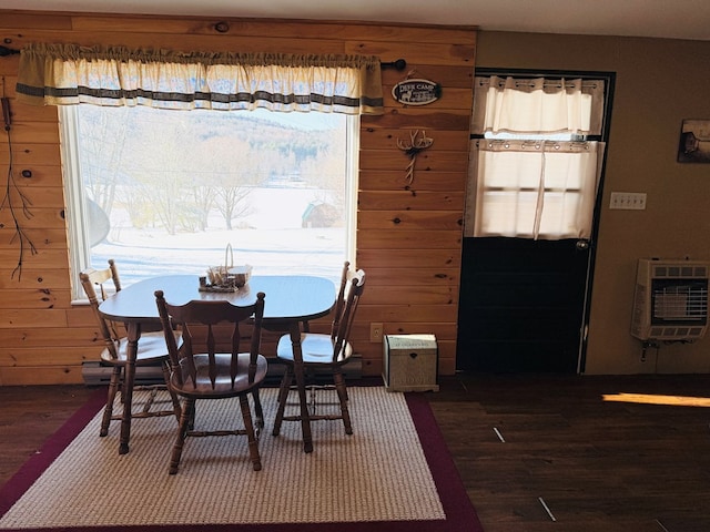 dining area with a wealth of natural light, wooden walls, heating unit, and dark hardwood / wood-style flooring