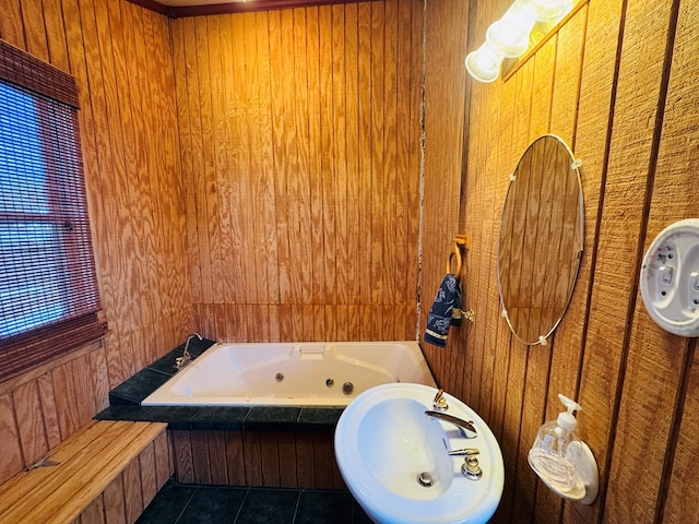 bathroom with sink, tiled bath, tile patterned flooring, and wood walls