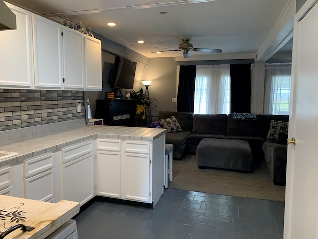 kitchen featuring backsplash, tile counters, white cabinetry, and kitchen peninsula