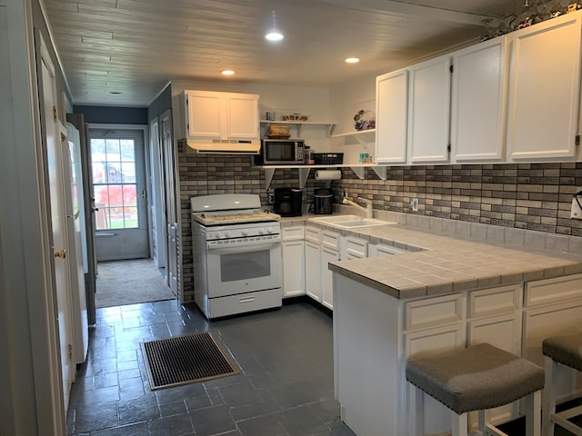 kitchen with tile countertops, white range, and white cabinetry