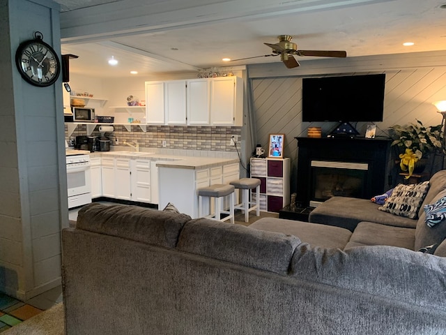 living room with ceiling fan, wood walls, and sink