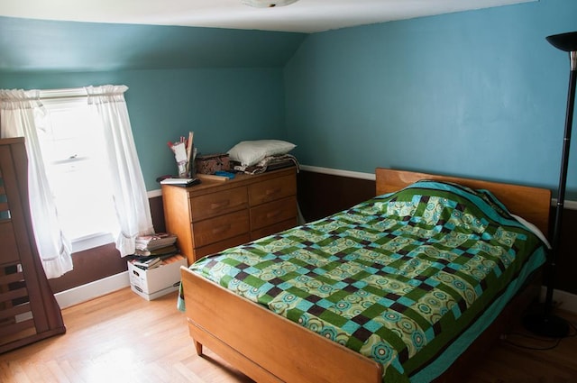 bedroom with multiple windows, vaulted ceiling, and light wood-type flooring