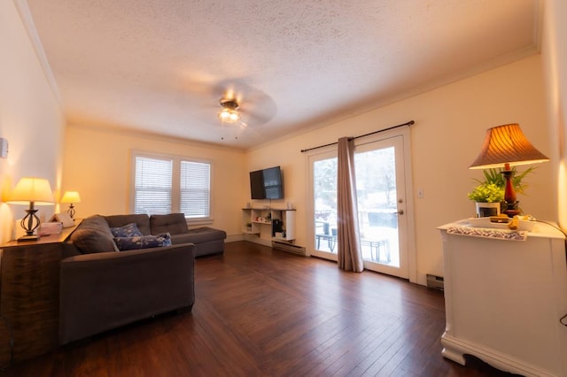 living room with a baseboard heating unit, a textured ceiling, ceiling fan, and ornamental molding