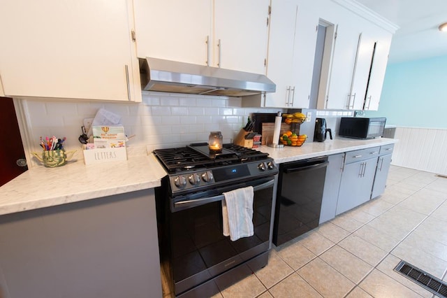 kitchen featuring white cabinetry, light stone counters, backsplash, light tile patterned floors, and black appliances