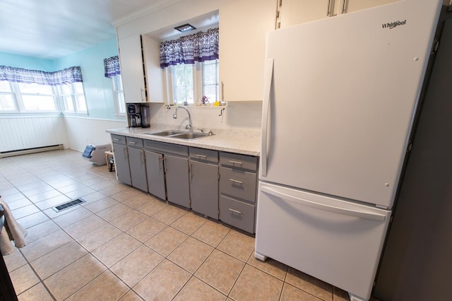 kitchen with light tile patterned floors, white refrigerator, gray cabinetry, and sink