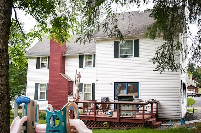 back of house featuring a playground and a wooden deck