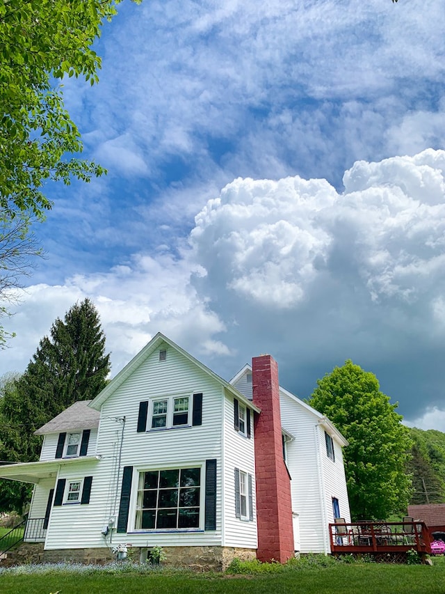 back of property with a lawn and a wooden deck