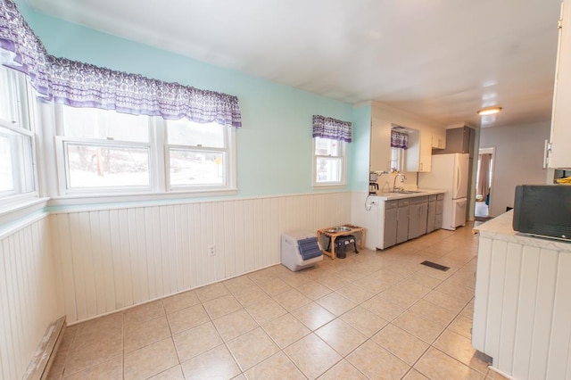 kitchen with white cabinetry, sink, white fridge, wooden walls, and light tile patterned floors