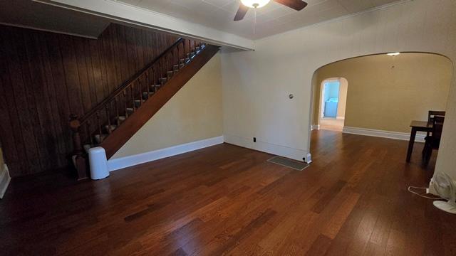 306 Broad St, Port Allegany, PA 16743 - unfurnished living room with arched walkways, a ceiling fan, wood finished floors, and stairs