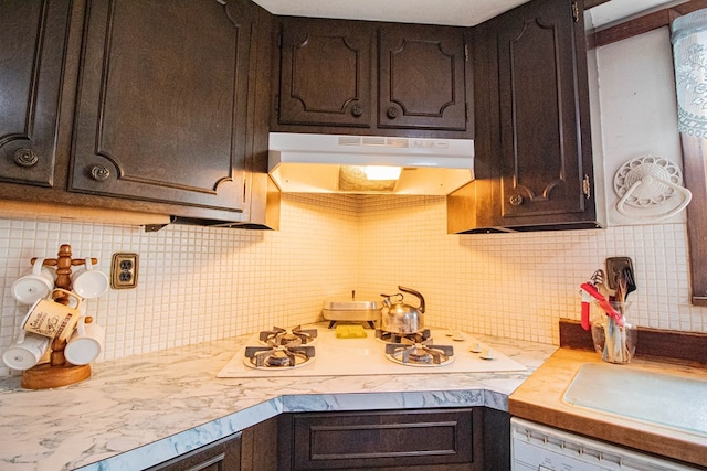 kitchen with dark brown cabinetry, decorative backsplash, dishwasher, and range hood