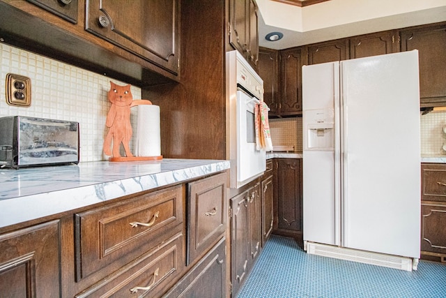 kitchen with tasteful backsplash, dark brown cabinets, and white appliances