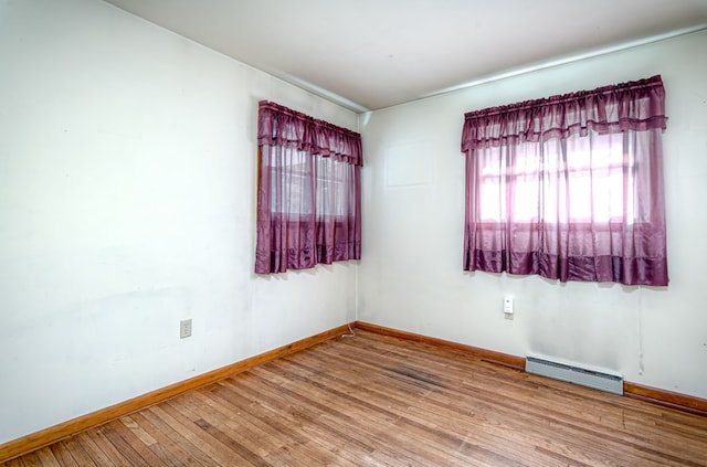 empty room featuring a baseboard radiator and wood-type flooring