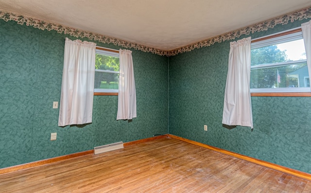 spare room with hardwood / wood-style floors and a baseboard heating unit