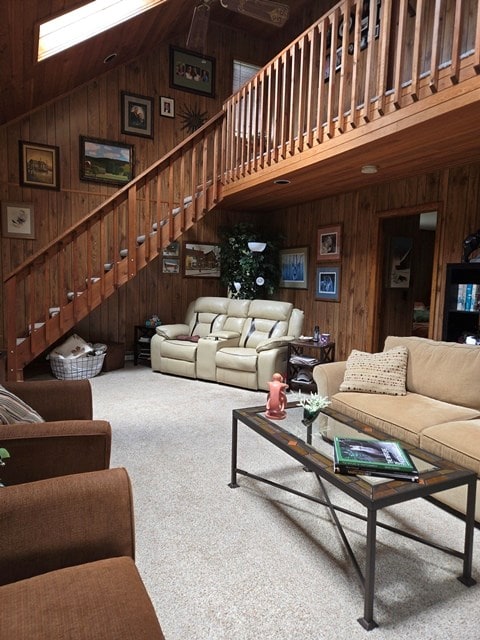 living room featuring carpet flooring, high vaulted ceiling, and wooden walls