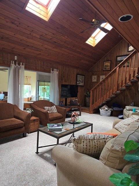 carpeted living room with ceiling fan, wood walls, wood ceiling, and lofted ceiling with skylight