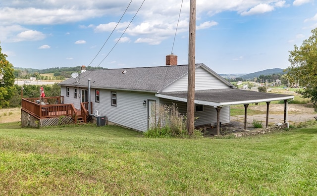 rear view of house with central air condition unit, a yard, and a deck with mountain view