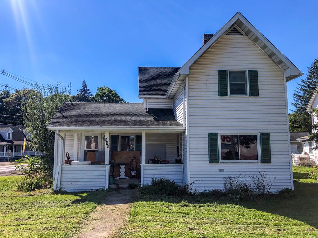 front facade featuring covered porch and a front yard