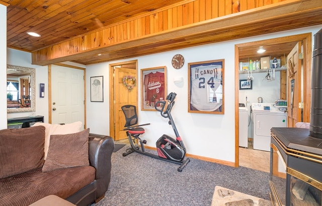 workout room featuring a wood stove, carpet, washer and clothes dryer, and wood ceiling