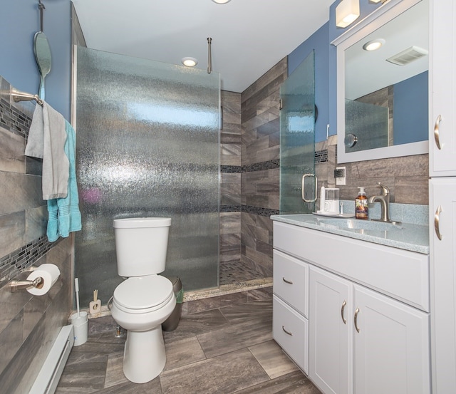 bathroom with a baseboard radiator, tile walls, a tile shower, toilet, and vanity