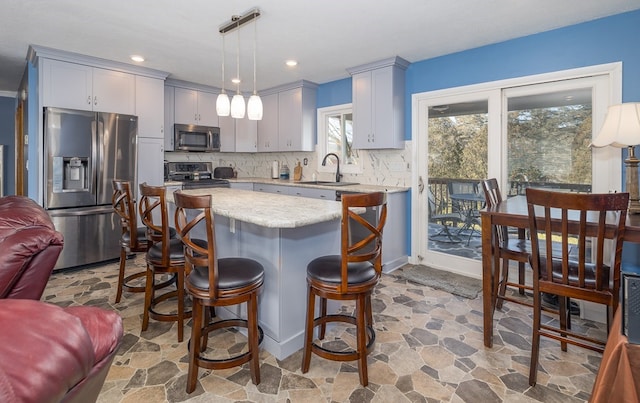 kitchen with a center island, appliances with stainless steel finishes, decorative backsplash, sink, and decorative light fixtures