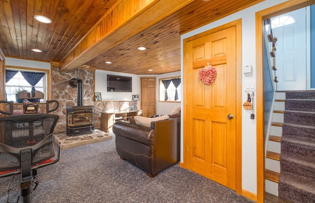 carpeted living room featuring wooden ceiling, a wood stove, and beamed ceiling