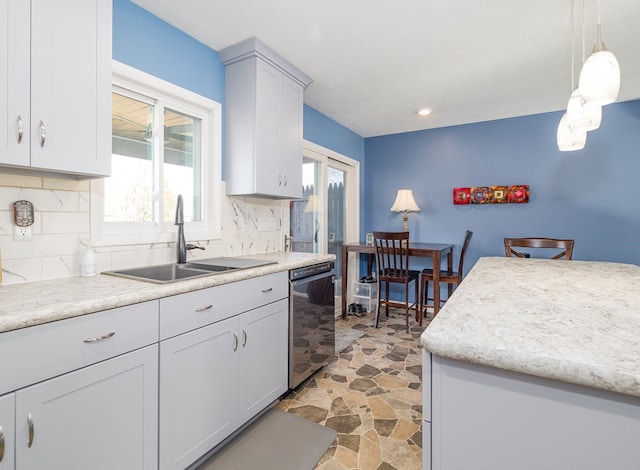 kitchen featuring decorative backsplash, sink, dishwashing machine, and decorative light fixtures