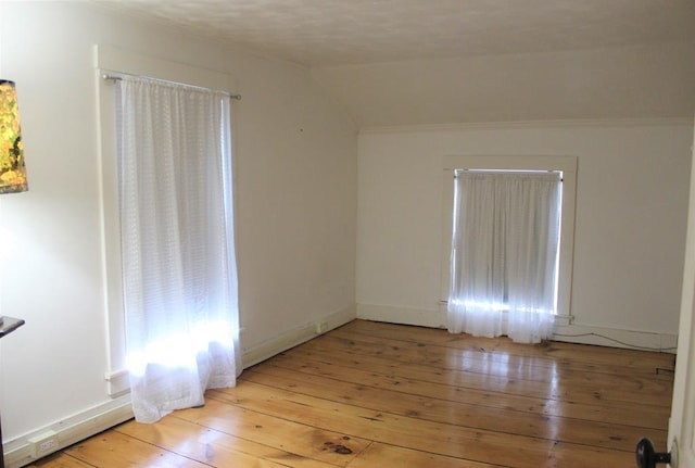 unfurnished room with light wood-type flooring, lofted ceiling, and baseboards