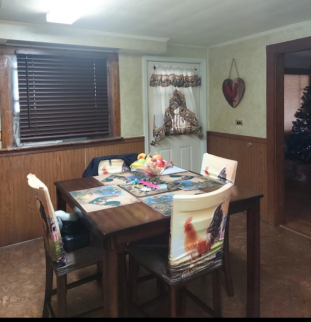 carpeted dining room featuring wooden walls, crown molding, and wainscoting