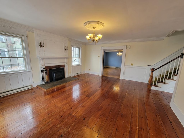 unfurnished living room featuring a baseboard heating unit, ornamental molding, hardwood / wood-style floors, and an inviting chandelier