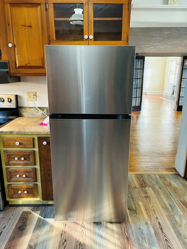 kitchen featuring stainless steel appliances, light stone counters, and light hardwood / wood-style flooring