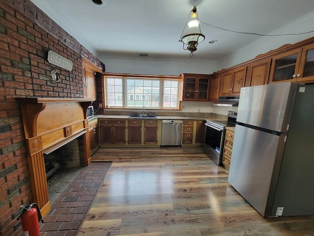 kitchen featuring sink, dark hardwood / wood-style floors, crown molding, stainless steel appliances, and brick wall