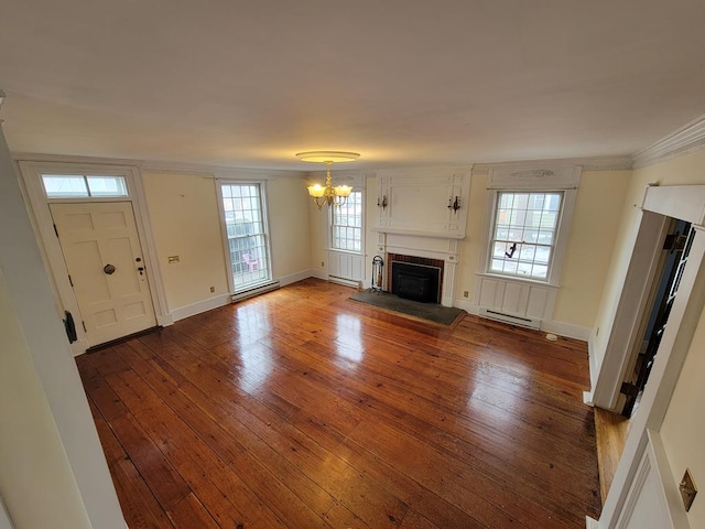 unfurnished living room with hardwood / wood-style floors, baseboard heating, crown molding, and a chandelier