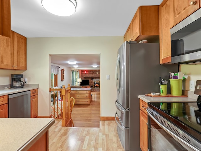 1817 Cotton Hollow Rd, Athens, PA 18810 - kitchen with appliances with stainless steel finishes, light wood finished floors, light countertops, a fireplace, and brown cabinetry