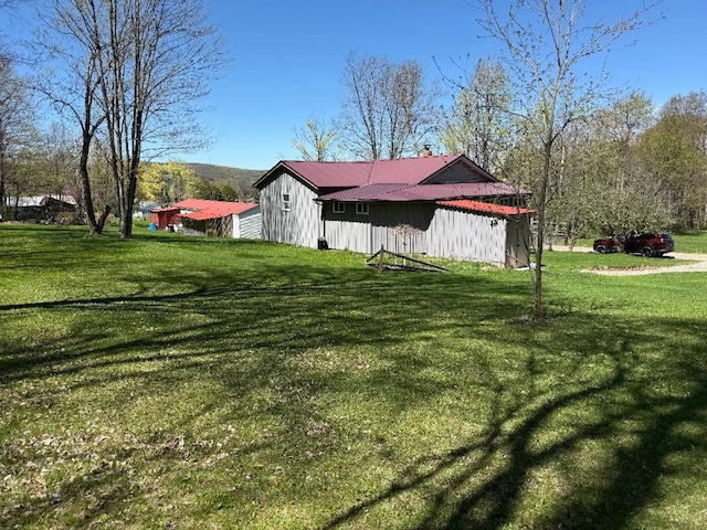 view of home's exterior with board and batten siding, a yard, a chimney, and metal roof