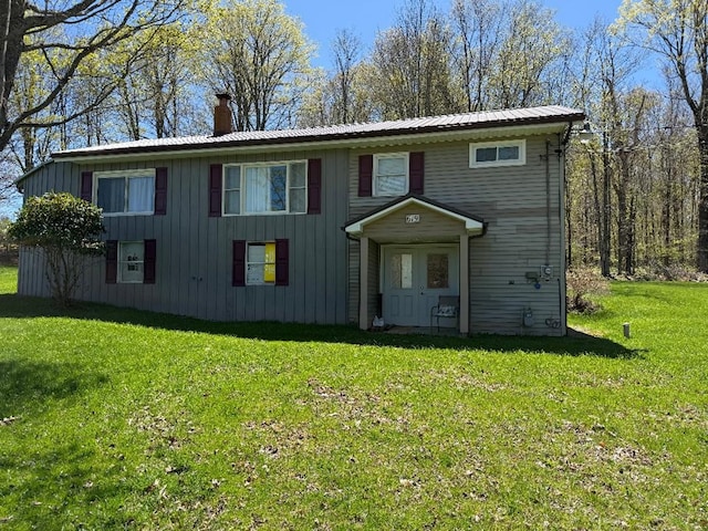 view of front of house featuring board and batten siding, a front yard, and a chimney