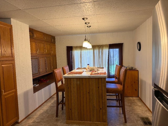 dining room featuring visible vents, baseboards, and wooden walls