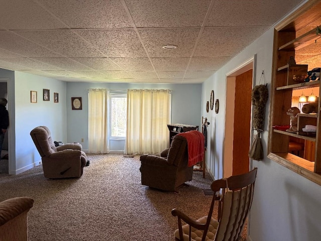 carpeted living area featuring baseboards, built in shelves, and a paneled ceiling
